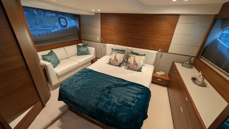  Yacht Photos Pics Luxurious bedroom interior of 2021 Princess V50 yacht with elegant wood paneling and plush bedding.