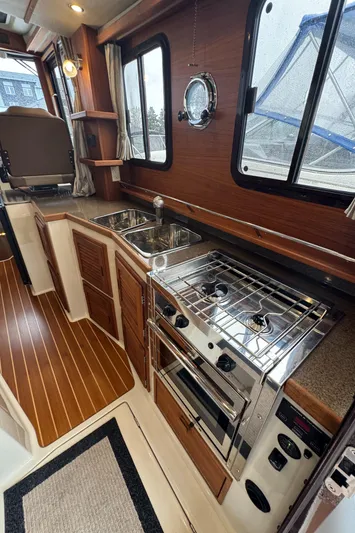  Yacht Photos Pics 2021 Ranger Tugs R-31 CB interior kitchen with stove, sink, and wooden cabinetry.