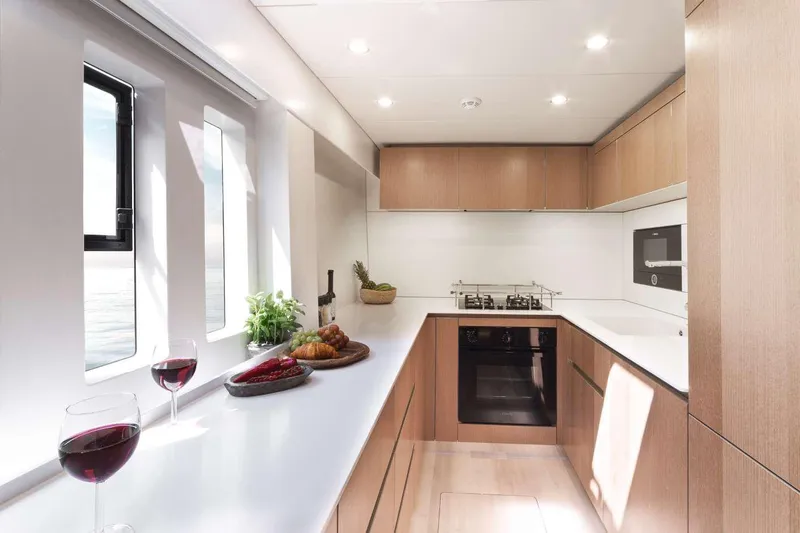 Betame Yacht Photos Pics Luxurious Sunreef 60 yacht kitchen interior with modern appliances and elegant wooden cabinetry, 2021 model.