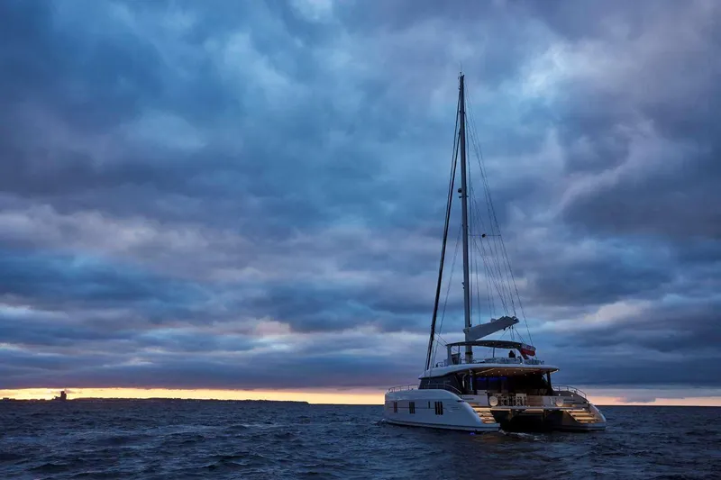 Betame Yacht Photos Pics Luxury Sunreef 60 yacht sailing at sunset under dramatic cloudy sky, 2021 model.