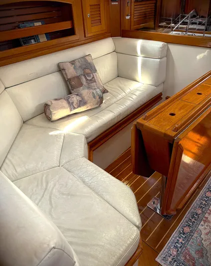 Aria Yacht Photos Pics Interior of 2000 Pacific Seacraft 37 yacht with white leather seating and wooden table.