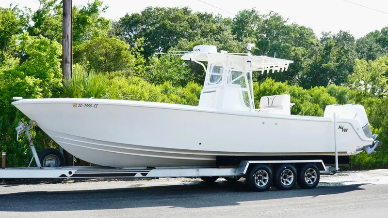  Yacht Photos Pics 2004 SeaVee 310B boat on trailer, parked outdoors with lush greenery in the background.