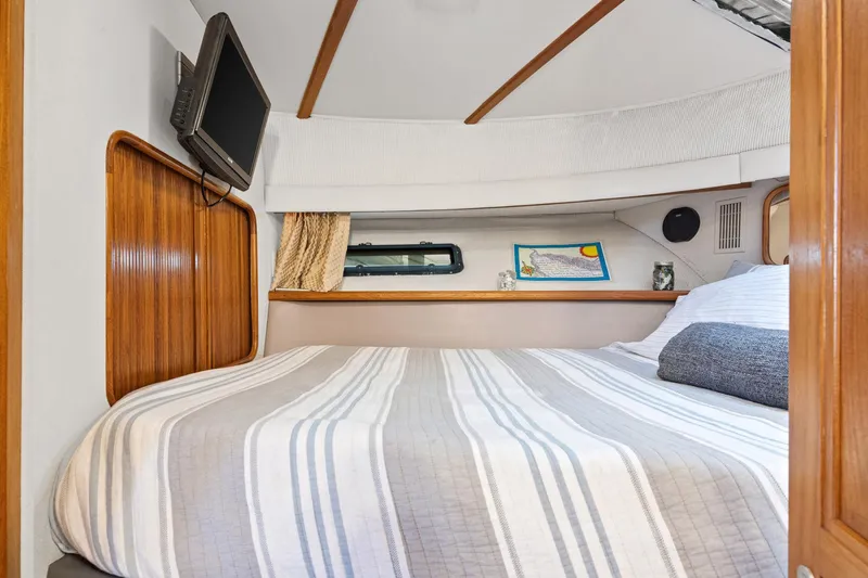 Perfectseas Yacht Photos Pics 1988 Carver 42 Aft Cabin Motoryacht bedroom with striped bedding and mounted TV.