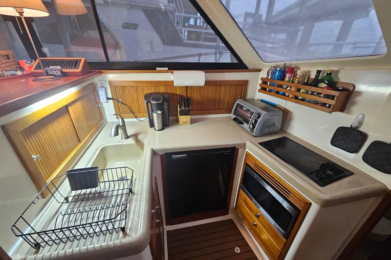  Yacht Photos Pics Compact kitchen in 1999 Riviera 40AC yacht with appliances and wooden cabinetry.
