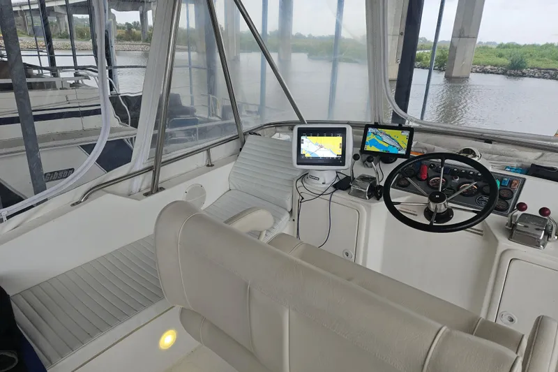  Yacht Photos Pics 1999 Riviera 40AC boat cockpit with navigation screens and steering wheel under a bridge.