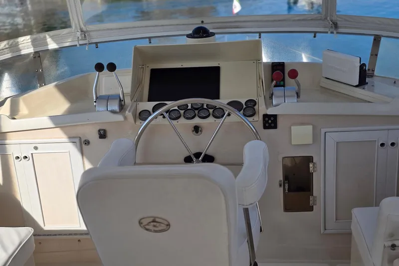 The Wetbar Yacht Photos Pics Helm of 1989 Offshore Yachts 48 Sedan with steering wheel and control panel.