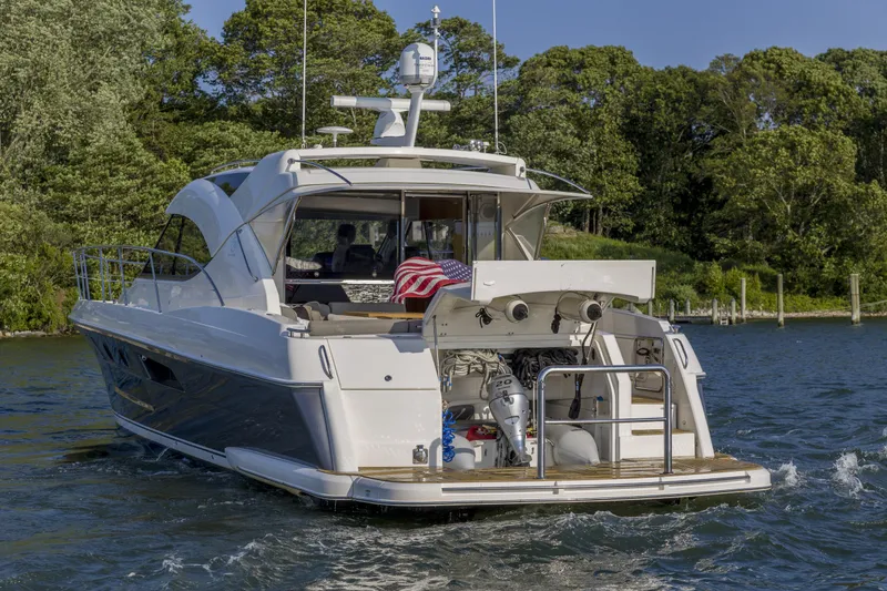 Pronto Yacht Photos Pics 2016 Riviera 5000 Sport Yacht cruising on a scenic waterway with lush greenery.