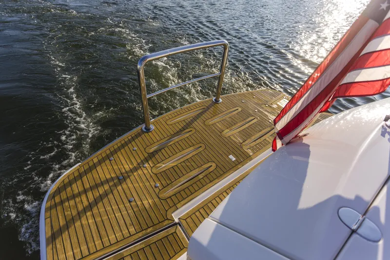 Pronto Yacht Photos Pics 2016 Riviera 5000 Sport Yacht with American flag on teak deck, cruising on water.