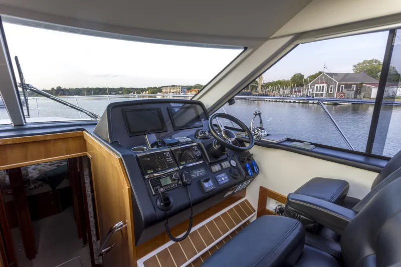 Pronto Yacht Photos Pics Interior helm of 2016 Riviera 5000 Sport Yacht with navigation controls and waterfront view.