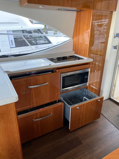 Pronto Yacht Photos Pics 2016 Riviera 5000 Sport Yacht kitchen with wood cabinetry, microwave, and dishwasher.