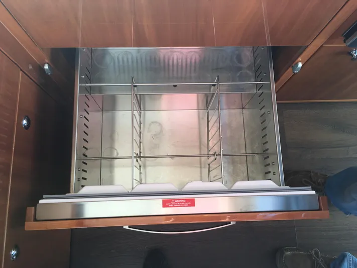 Pronto Yacht Photos Pics Open drawer in 2016 Riviera 5000 Sport Yacht, featuring stainless steel interior and wooden finish.