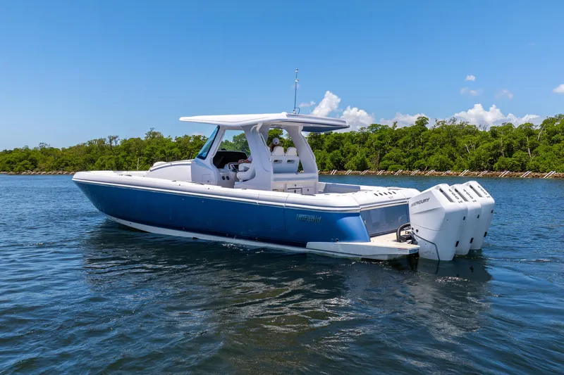 Yacht Photos Pics 2025 Intrepid 41 Panacea boat on water, blue hull, triple outboard engines, clear sky.