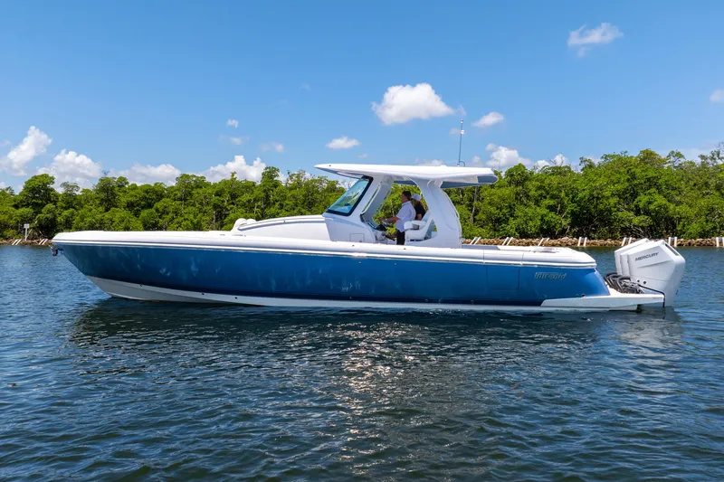  Yacht Photos Pics 2025 Intrepid 41 Panacea boat on water, clear sky, lush green background.