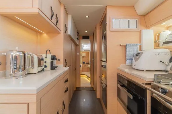 Hindsight Yacht Photos Pics Modern kitchen interior of 2016 Jeanneau 64 yacht with appliances and light wood cabinetry.