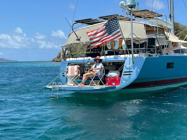 Hindsight Yacht Photos Pics 2016 Jeanneau 64 yacht anchored in clear blue waters with an American flag.