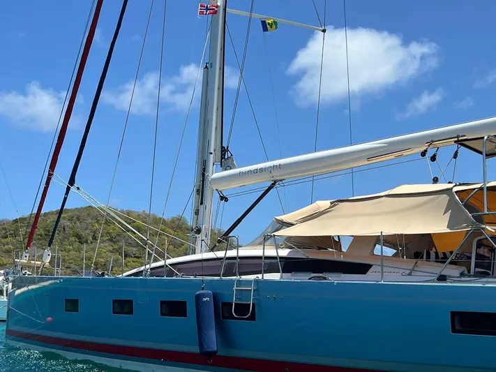 Hindsight Yacht Photos Pics 2016 Jeanneau 64 sailboat with blue hull anchored near a scenic coastline.