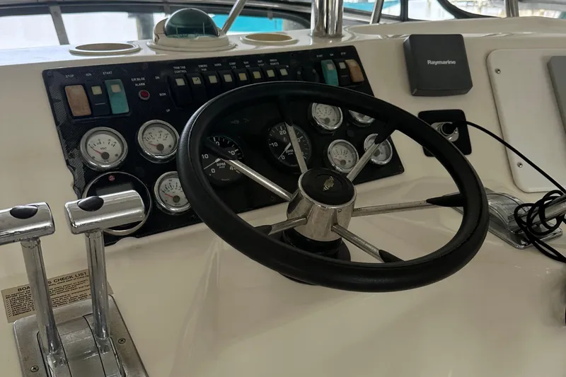 Tracy II Yacht Photos Pics Steering wheel and dashboard of a 2002 Riviera 350 boat, featuring gauges and controls.