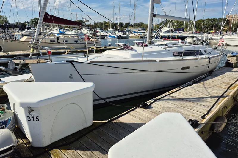 Serene Yacht Photos Pics 2011 Beneteau Oceanis 37 sailboat docked at a marina, surrounded by other boats.