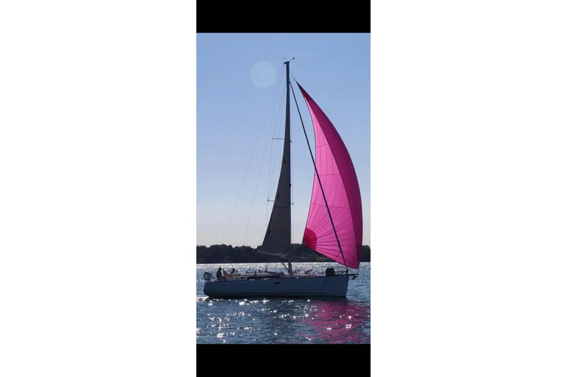 Serene Yacht Photos Pics Sailing yacht Beneteau Oceanis 37 (2011) with vibrant pink sail on calm water.