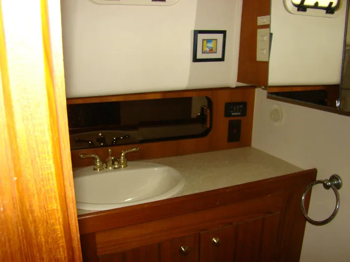 Good Chemistry Yacht Photos Pics 2001 Mainship 430 Trawler bathroom with sink, mirror, and wooden cabinetry.