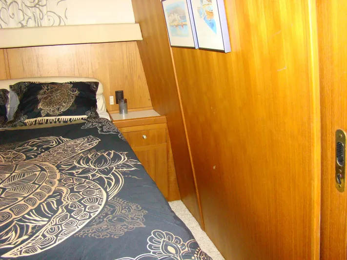 Good Chemistry Yacht Photos Pics 2001 Mainship 430 Trawler bedroom with wooden paneling and patterned bedding.