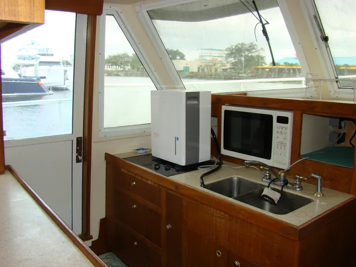 Good Chemistry Yacht Photos Pics Mainship 430 Trawler 2001 kitchen area with sink, microwave, and window view.
