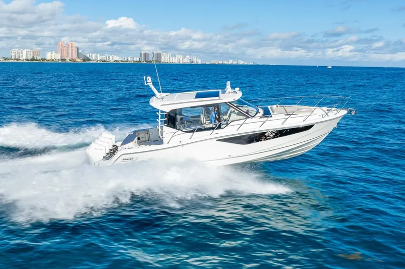 True Companion Yacht Photos Pics 2024 Boston Whaler 405 Conquest cruising on blue ocean near city skyline.