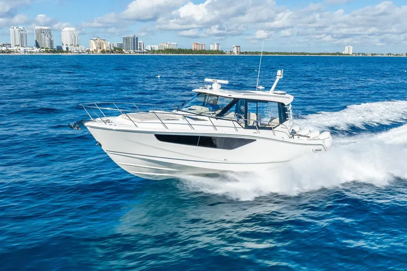 True Companion Yacht Photos Pics 2024 Boston Whaler 405 Conquest cruising on blue ocean near city skyline.