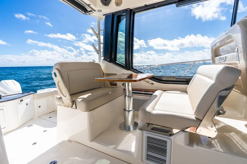 True Companion Yacht Photos Pics 2024 Boston Whaler 405 Conquest interior with ocean view, featuring comfortable seating and table.