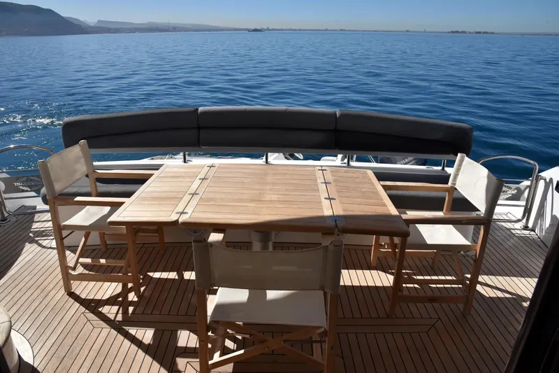Bar&co Yacht Photos Pics Luxury Sunseeker Manhattan 73 yacht deck with wooden table and chairs, ocean view.