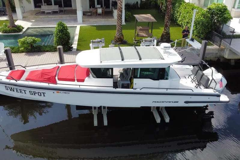 Sweet Spot Yacht Photos Pics 2021 Axopar 37 Cross Cabin boat docked near a modern waterfront home.