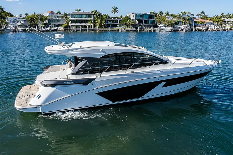  Yacht Photos Pics 2022 Beneteau Gran Turismo 45 luxury yacht cruising in a scenic waterfront area.