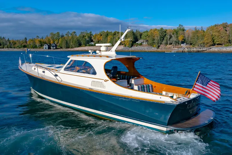 Charmer Yacht Photos Pics 1999 Hinckley Talaria 44 Express yacht cruising on a scenic lake with American flag.