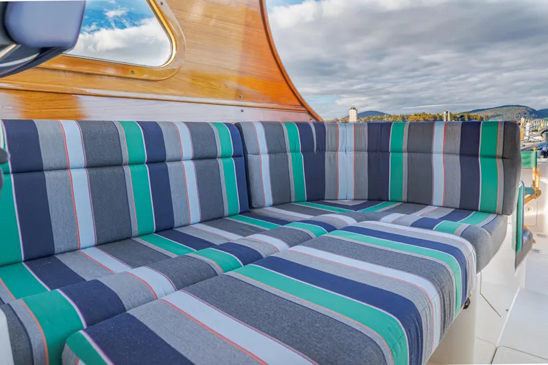 Charmer Yacht Photos Pics Striped seating on 1999 Hinckley Talaria 44 Express yacht, with wooden accents and scenic backdrop.