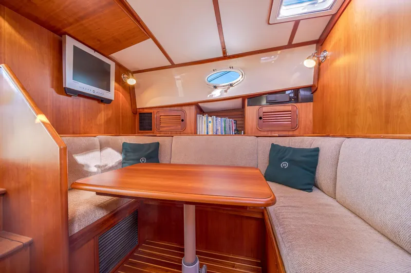 Charmer Yacht Photos Pics Interior of 1999 Hinckley Talaria 44 Express yacht with cozy seating and wooden table.