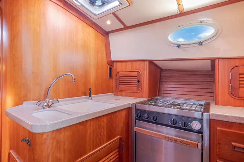 Charmer Yacht Photos Pics Hinckley Talaria 44 Express 1999 yacht kitchen with wood cabinetry and stainless steel stove.