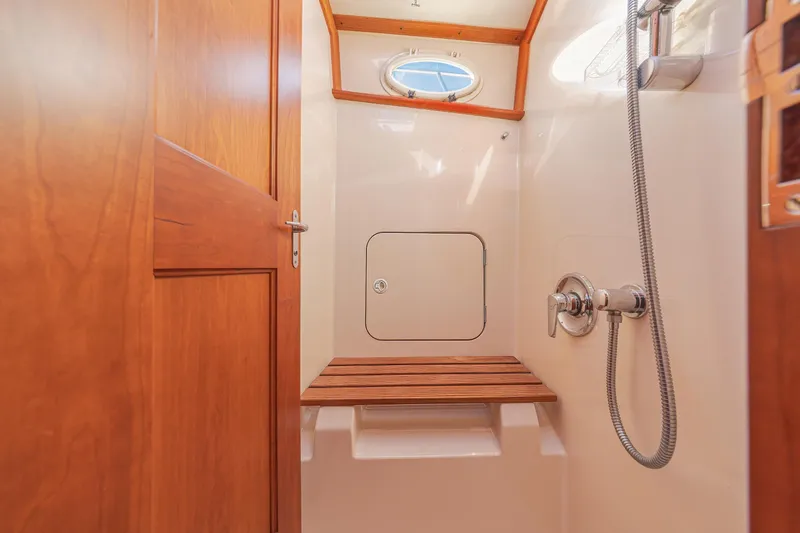 Charmer Yacht Photos Pics Hinckley Talaria 44 Express 1999 yacht shower with wooden bench and porthole window.