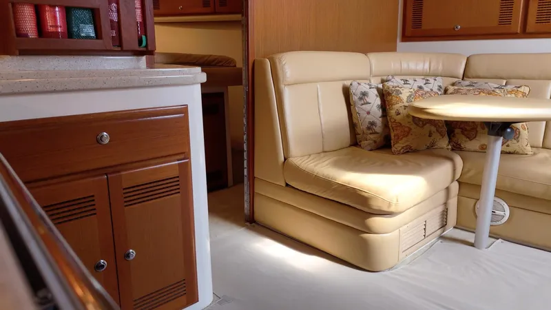 Siboney Yacht Photos Pics Interior of a 2004 Cabo 40 Express yacht with beige sofa and wooden cabinetry.