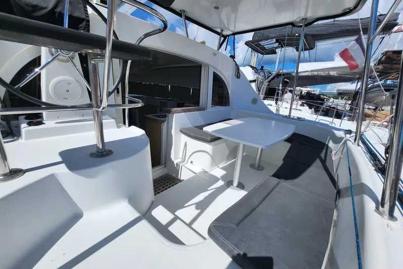Arcane Yacht Photos Pics Lagoon 380 catamaran cockpit with seating and table, showcasing modern design and comfort.