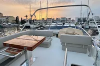 2017 Cranchi E 52 F yacht deck at sunset, featuring elegant seating and a wooden table.
