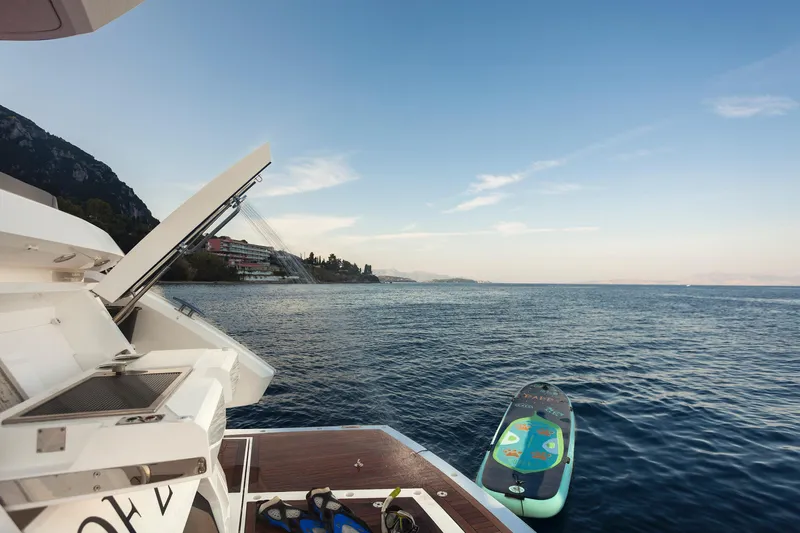 M/y Lady K Yacht Photos Pics 2018 Sunseeker Manhattan 52 yacht with paddleboard on serene water.