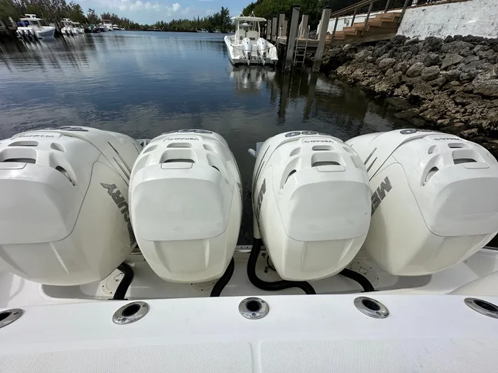  Yacht Photos Pics Boston Whaler 420 Outrage 2020 with four Mercury outboard engines docked by a serene waterway.