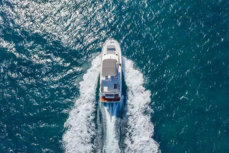 Carolina Blues Yacht Photos Pics 2025 Beneteau Swift Trawler 41 Fly cruising on open blue sea, aerial view.