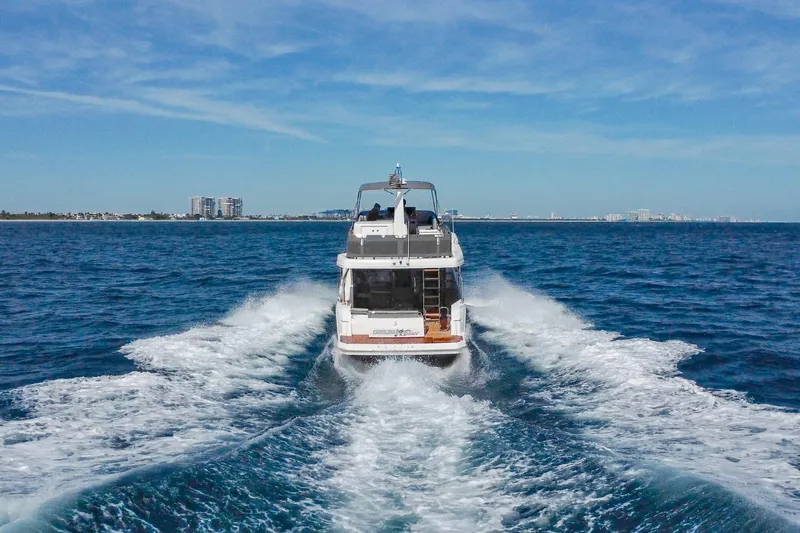 Carolina Blues Yacht Photos Pics 2025 Beneteau Swift Trawler 41 Fly cruising on open sea, city skyline in background.