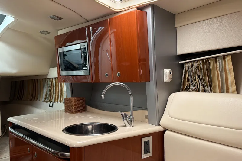  Yacht Photos Pics 2009 Formula 350 Sun Sport interior with kitchenette, featuring sink, microwave, and elegant wood cabinetry.