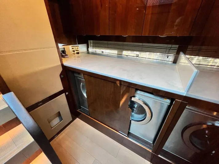 Blind Date Yacht Photos Pics Laundry area in 2020 Fairline Squadron 68 yacht with modern appliances and wooden cabinetry.