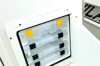 Storage compartment on 2023 Aquila 28 Molokai boat, featuring organized plastic containers.