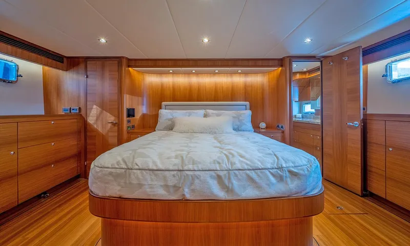 Our Way III Yacht Photos Pics Luxurious bedroom interior of 2023 Outer Reef Yachts 720 Motoryacht with wood paneling and cozy lighting.