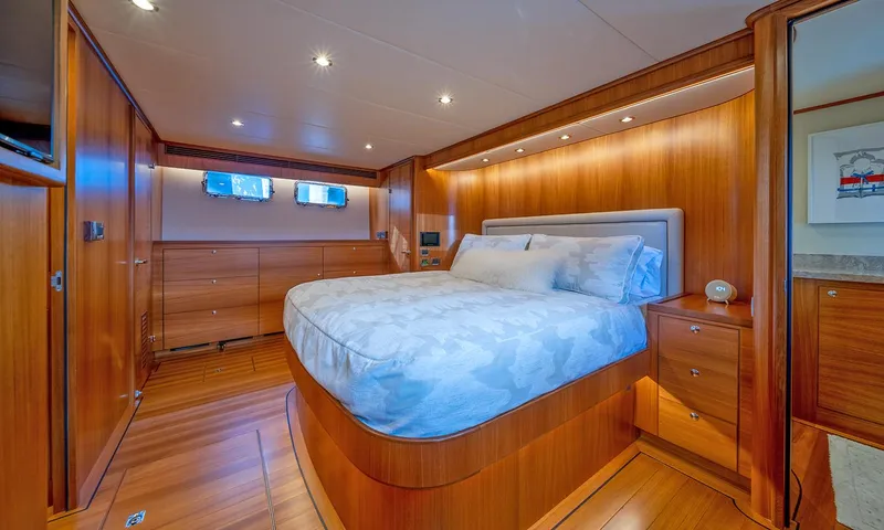 Our Way III Yacht Photos Pics Luxurious bedroom interior of 2023 Outer Reef Yachts 720 Motoryacht with wood paneling and cozy bed.