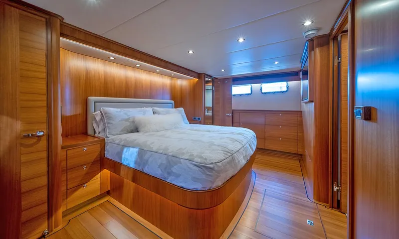 Our Way III Yacht Photos Pics Luxurious bedroom interior of 2023 Outer Reef Yachts 720 Motoryacht with wood paneling and modern lighting.